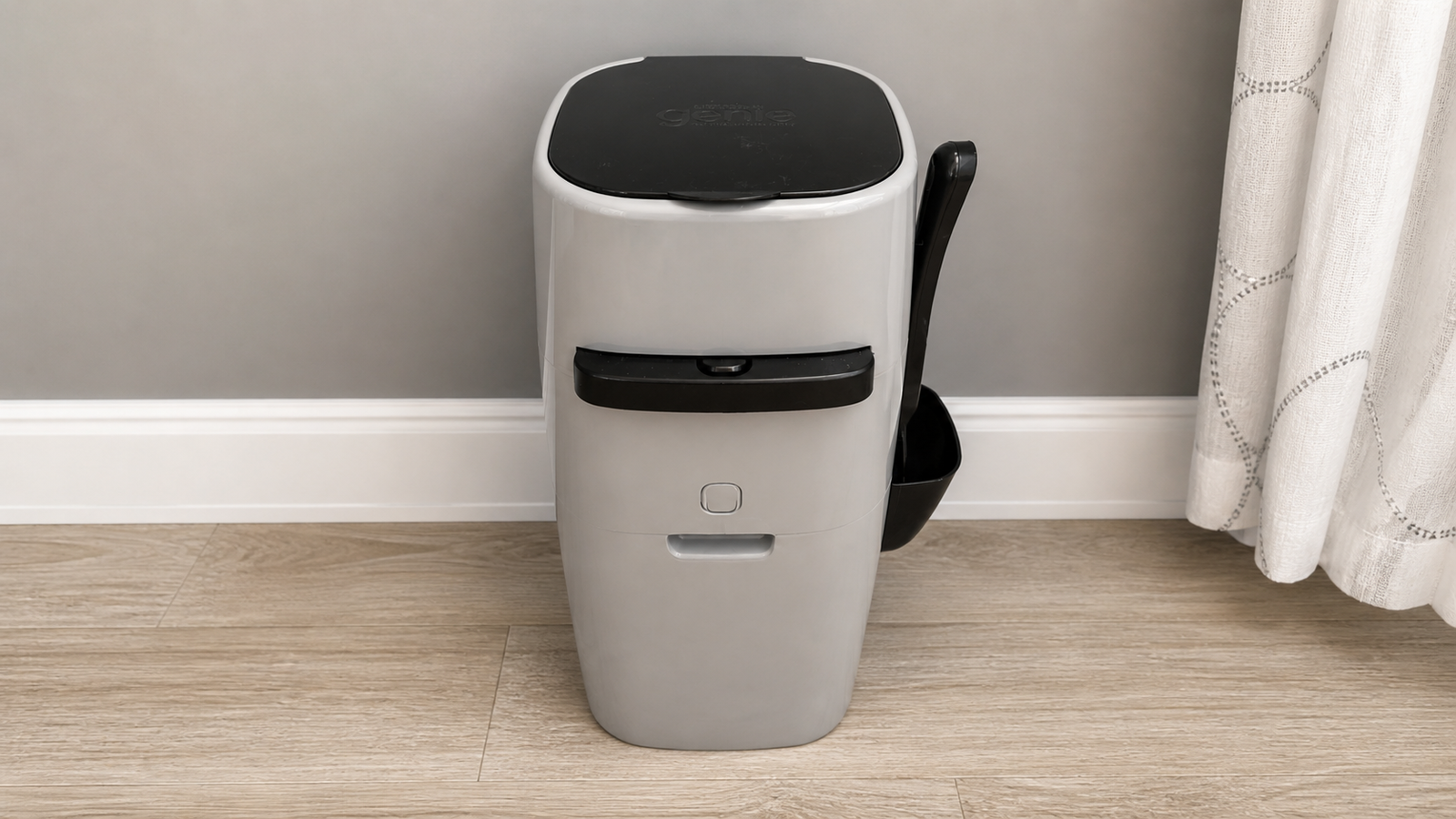 Litter Genie cat litter disposal pail centered on light wood flooring against a soft gray wall, with attached scoop